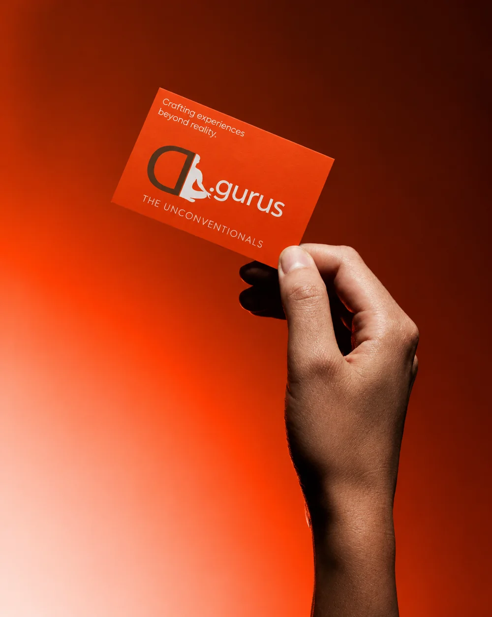 A D'Gurus business card held up against an orange light